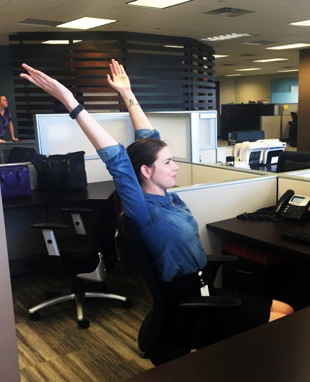 A woman stretches at her desk