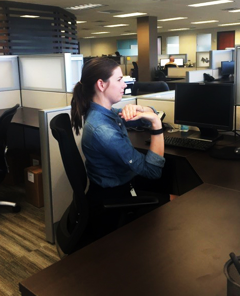 A woman stretches at her desk