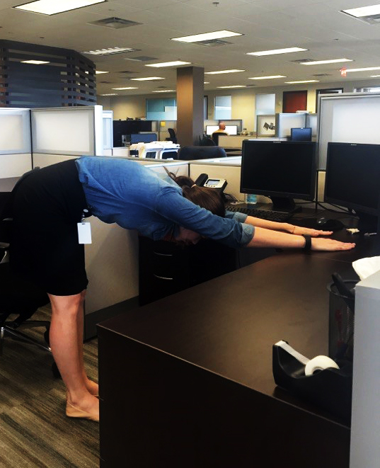 A woman stretches at her desk