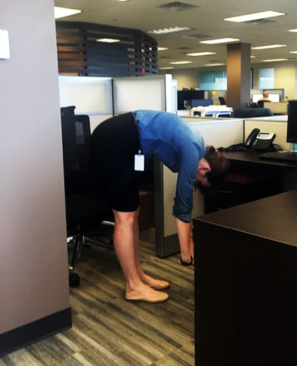 A woman stretches at her desk